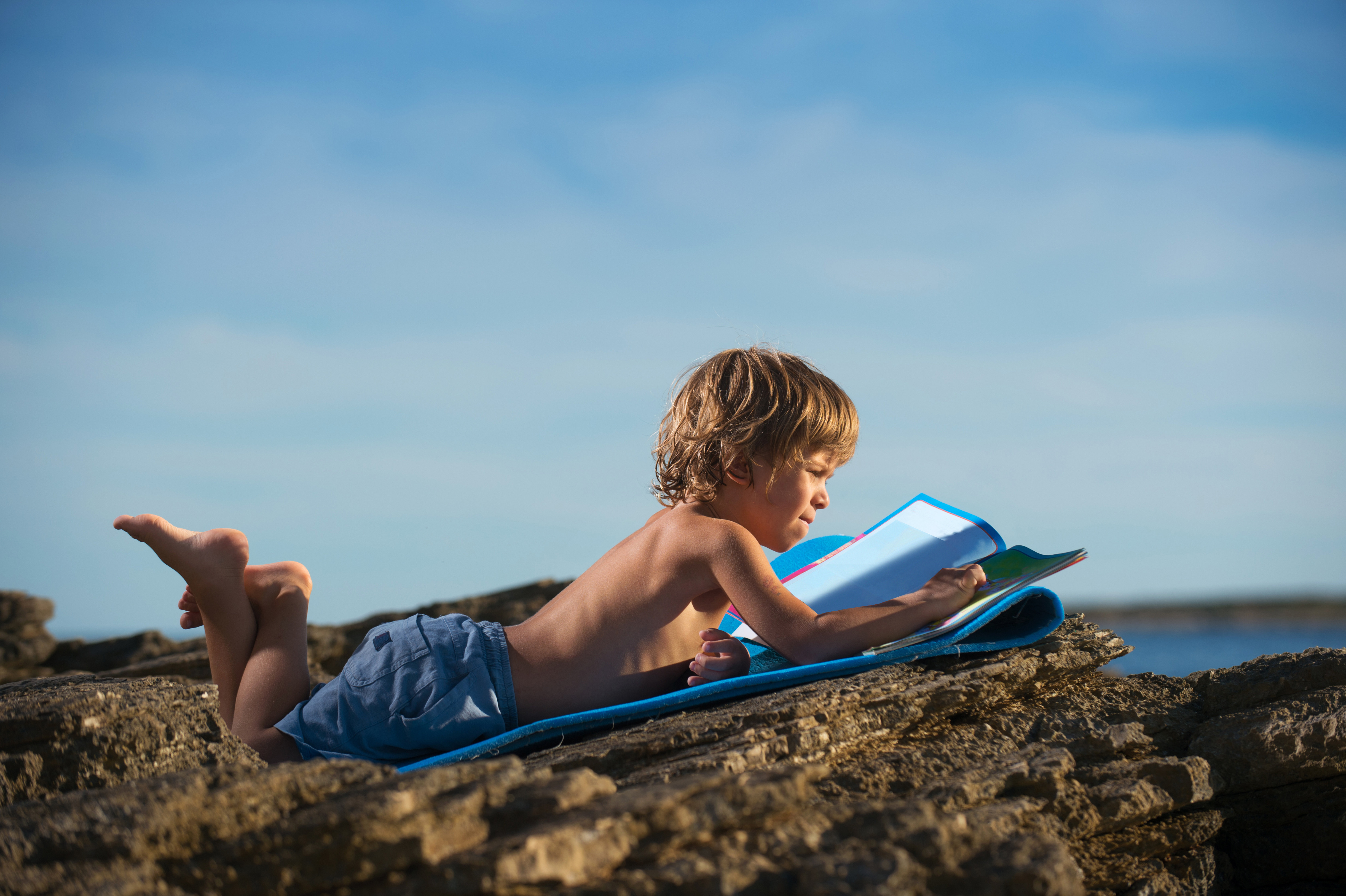 enfant sur la plage avec son cahier de vacances