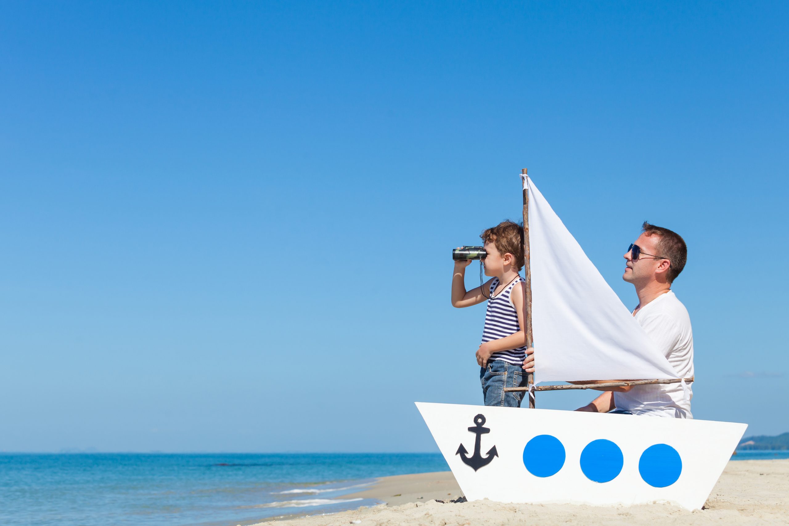 Père et fils jouent sur une barque à la plage