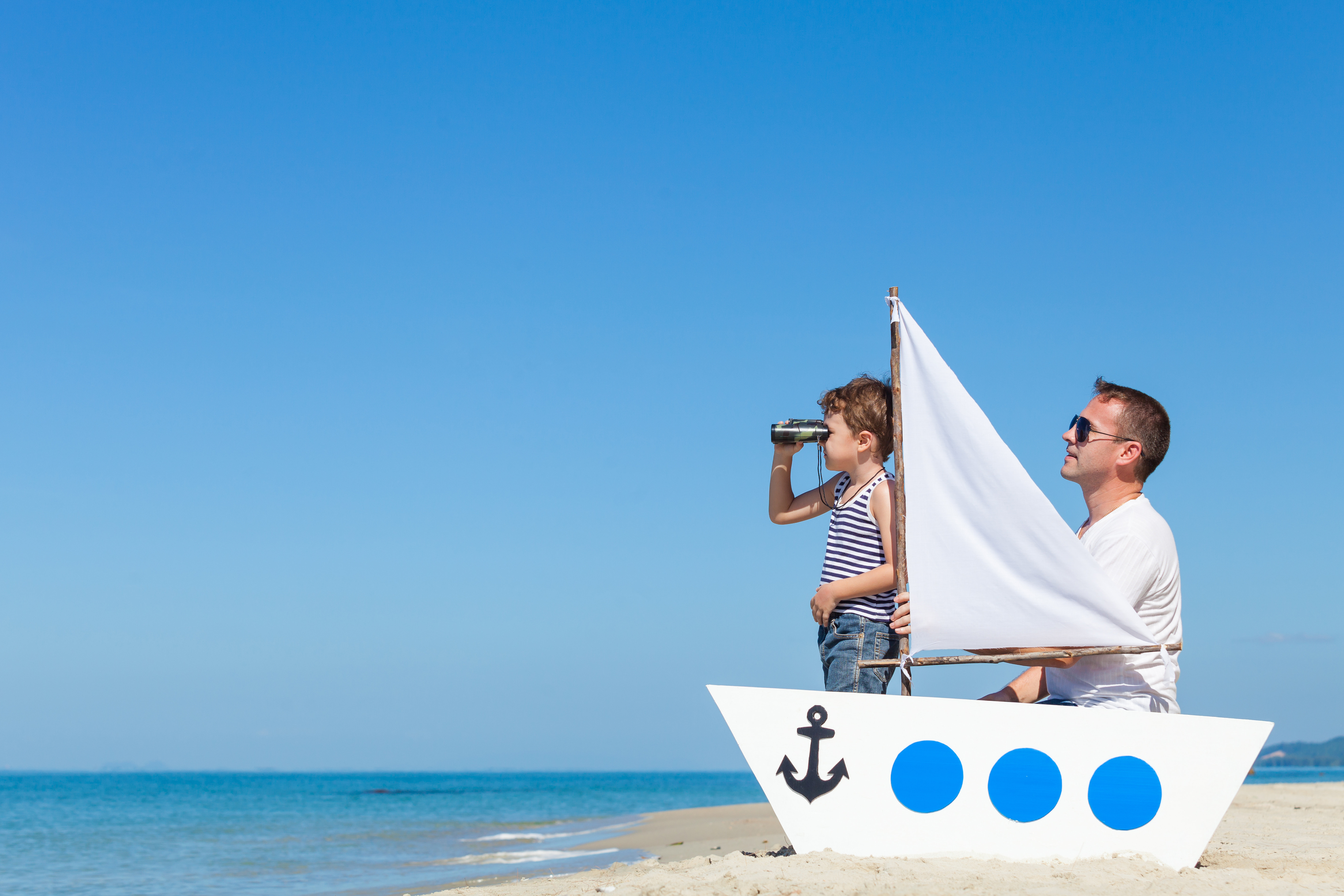 Père et fils jouent sur une barque à la plage